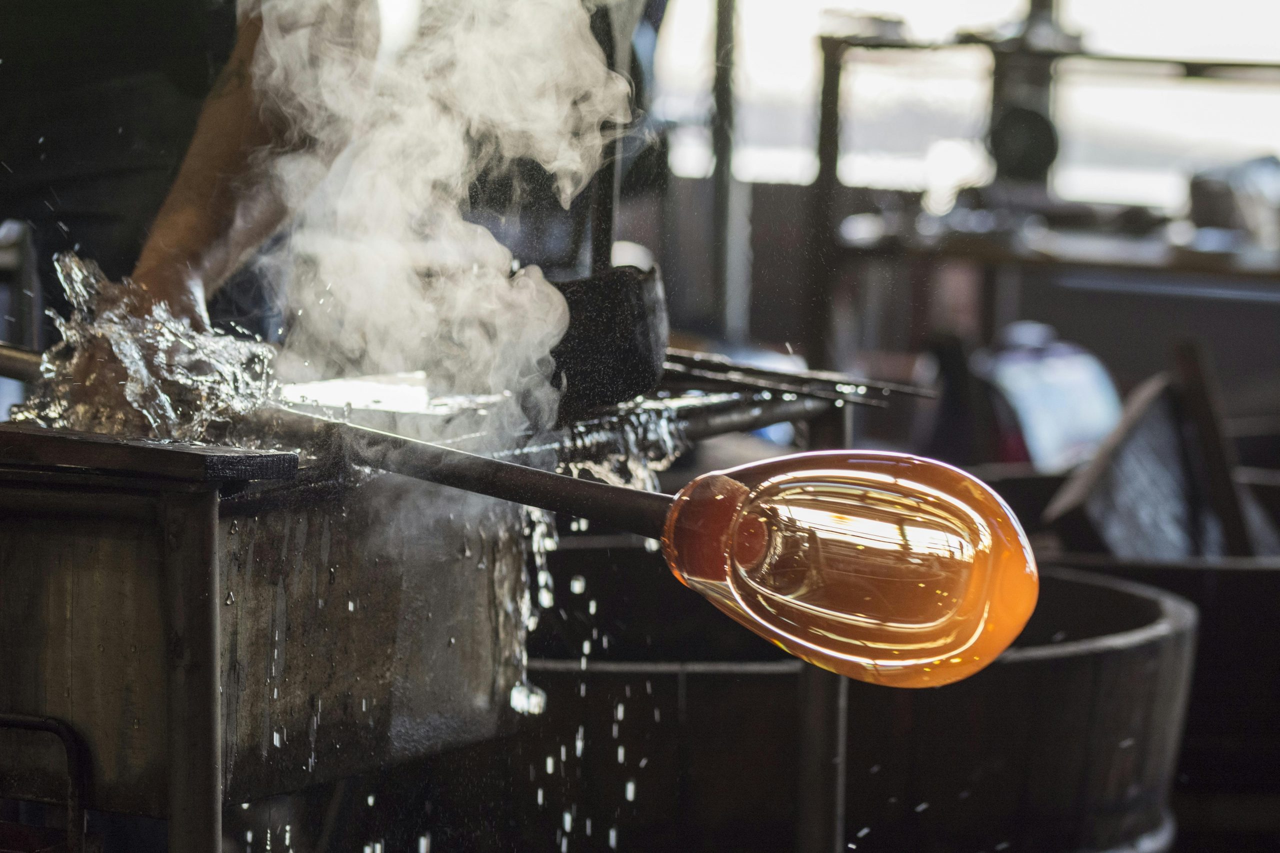 A skilled artisan involved in the intricate process of glass blowing, highlighting craftsmanship.