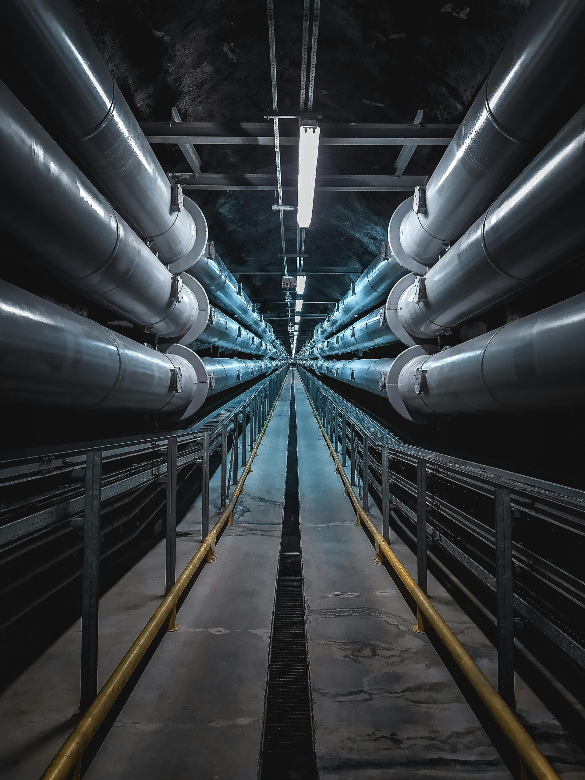 A dramatic view of a symmetric industrial tunnel lined with steel pipes.