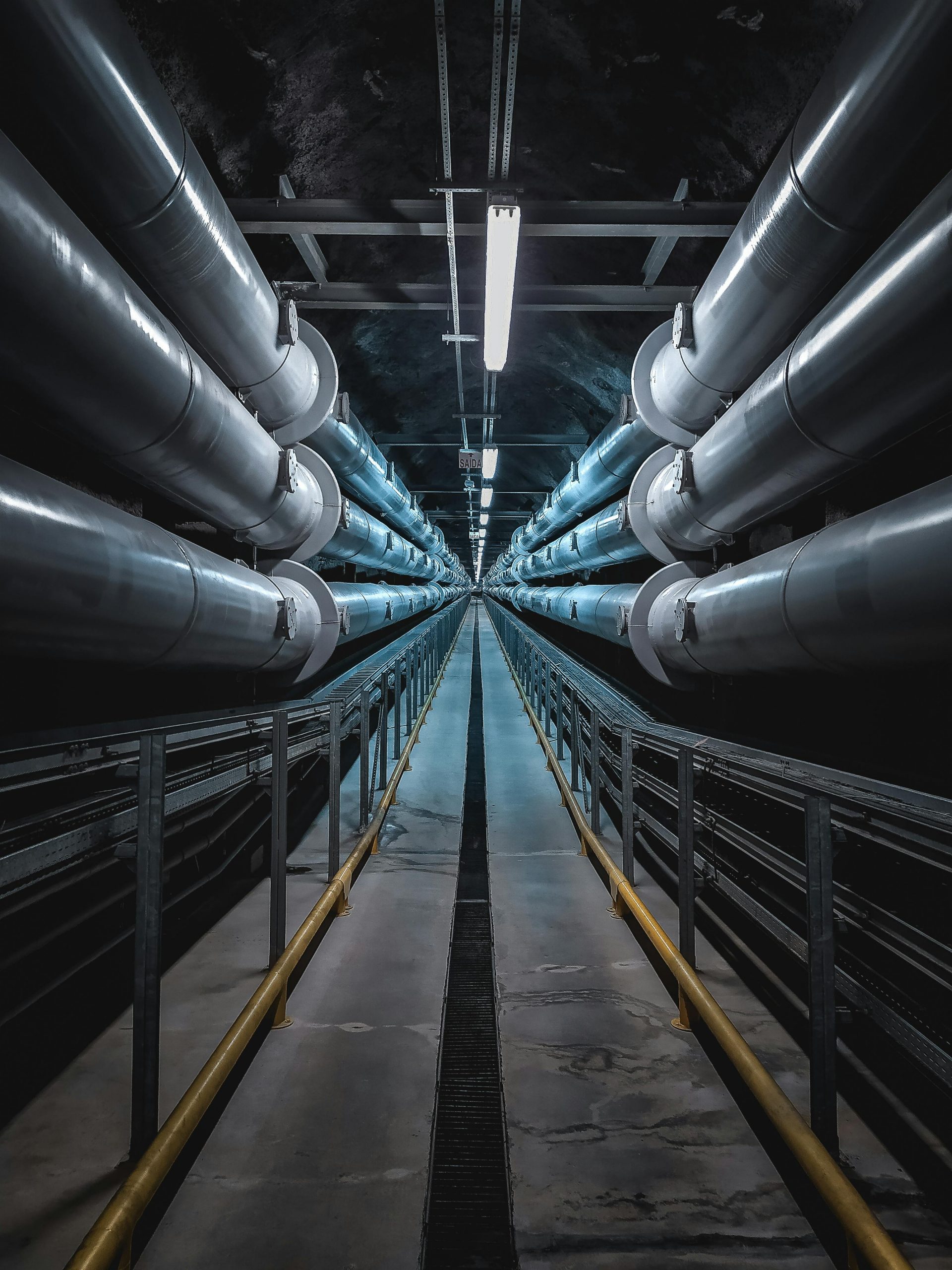 A dramatic view of a symmetric industrial tunnel lined with steel pipes.