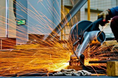 pexels-photo-1145434-1145434 A worker operates a grinder cutting metal, creating a vibrant display of sparks in an industrial setting.